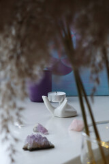 Altar with crystals and extinguished candle on ceramic stand in the form of a hand. Beautiful home decor.