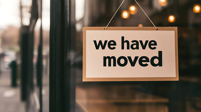 Announcement of relocation: A sign on a door declares 'we have moved'. The lighting is soft, with blurred reflections visible in the glass.