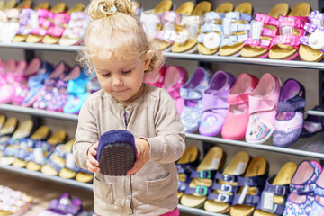 A little girl tries on children's shoes in a shoe store in a shopping mall.