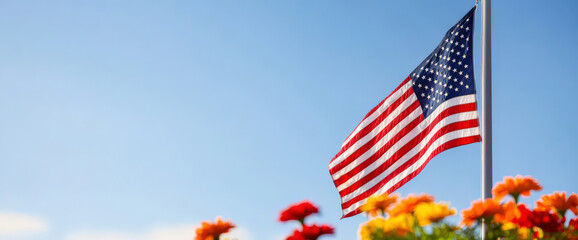 American flag waving against clear blue sky, surrounded by vibrant flowers. symbol of patriotism and remembrance