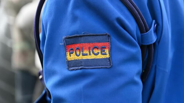 The chevron "Police" on the sleeve of a blue police suit in Nairobi. Kenya, Africa. AI-generated item
