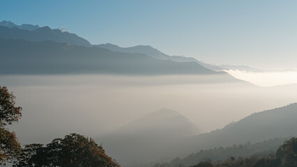 TADAPANI, NEPAL - JANUARY 11, 2025: Morning sunlight highlights the majestic hills covered in fog in Annapurna region, ample copy space.