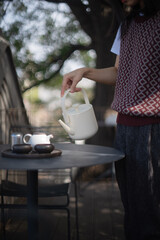 A girl is making making tea under a tree, a beautiful teapot set, peaceful life, heathy life 