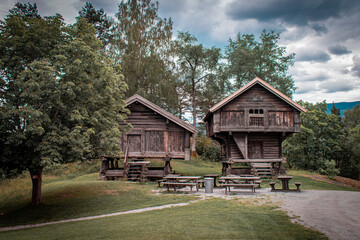 Wooden Norwegian cabins with tables and benches in front.
