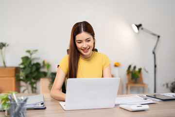 Executive freelance woman using laptop for remote work from home, young woman in casual wear sits at desk in living room at home, texting, typing, writing an article, sending emails, chatting online.