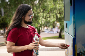 Young hispanic man using bottle deposit point. Man recycling plastic bottle via reverse vending...