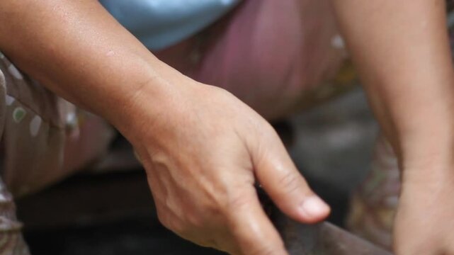 woman's hand holding a knife cutting raw spinach