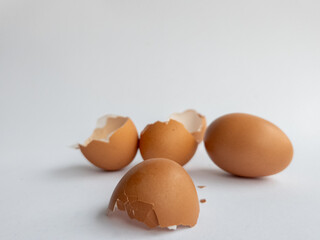 Several pieces of broken chicken egg shells and intact chicken eggs isolated on white background