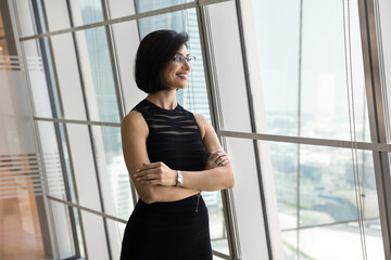 Forward thinking vision. Confident smiling mature businesswoman stand alone with arms crossed enjoy...