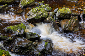 Naklejka premium Dynamic Water Flow Over Ancient Stones at The Birks of Aberfeldy, Perthshire: Captivating Natural Scenery in the Heart of Scotland’s Woodland