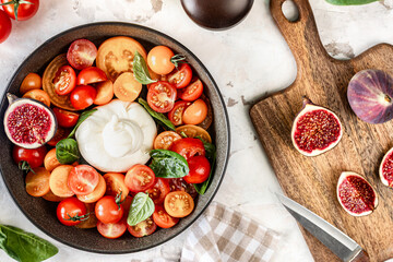 Salad with traditional italian burrata cheese with spinach, cherry tomatoes, figs and olive oil.