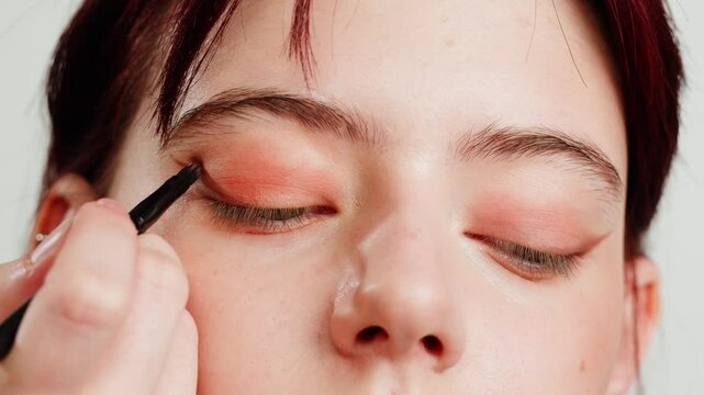 Eye shadow makeup to the upper eyeliner, close-up. Makeup artist applies a bright eye shadow with a makeup brush.Tutorial master class of professional makeup. 
