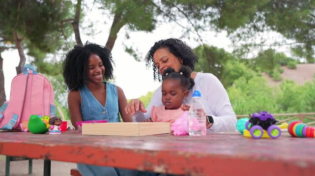 Multigenerational african american family sharing playful moments together, enjoying leisure time at park table with toys, smiling and connecting