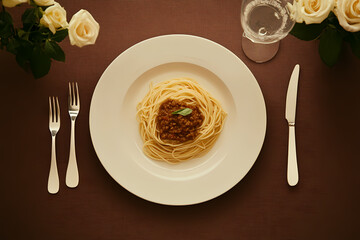 spaghetti Bolognese on a white plate, restaurant table setting with cutlery and flowers