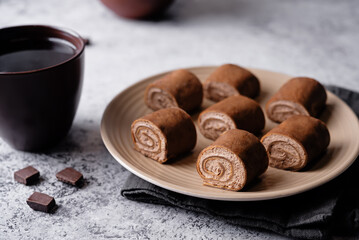 Chocolate crepe rolls with chocolate whipped cream filling in a plate