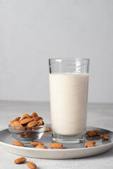 Fresh almond milk in tall glass on gray plate, Healthy vegan milk replacer