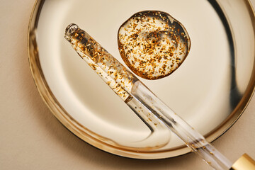 24 k gold facial serum in a pipette on a gold background.