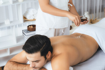 Blissful man customer having exfoliation treatment in luxury spa salon with warmth candle light...