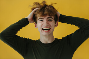 Young Man Laughing Playfully on Yellow Background Showing Joyful Expression