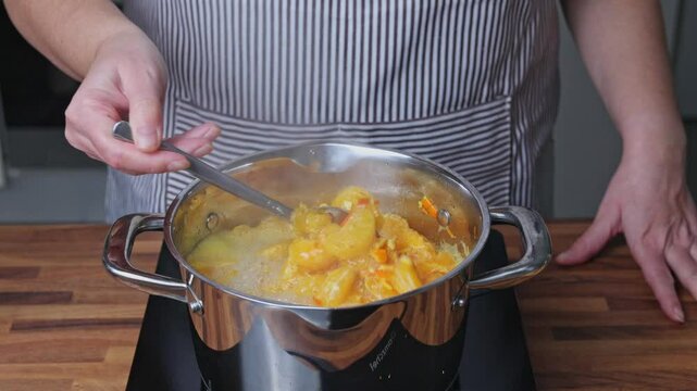 Cooking tangerine jam in a saucepan on the stove in a home kitchen