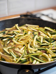 Delicious preparation of sliced zucchini and onion in a sizzling skillet creating a mouthwatering aroma in a home kitchen