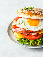Delicious breakfast burger with egg, ham, cheese, tomato, and lettuce on sesame bun