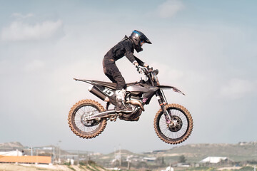 Professional motocross rider performing a jump during a race with blurred background