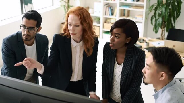 Creative business team meeting in modern start up office female team leader pointing at screen discussing diverse people group teamwork