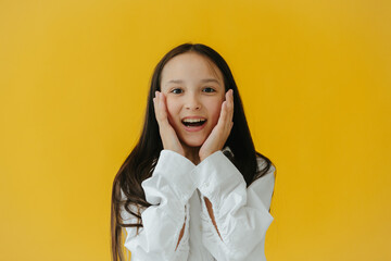 Smiling Girl Expressing Joy Against a Bright Yellow Studio Background