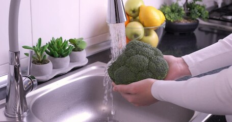Woman hands washing fresh broccoli in the kitchen. Eating healthy raw organic food, vitamins, washing vegetables from pesticides concept. Slow motion 4k - Powered by Adobe