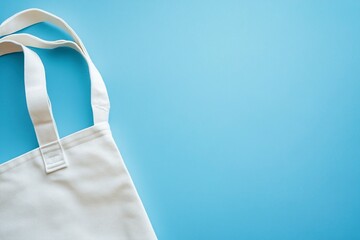 White blank tote bag mockup, blue background, stock photo for product design template, close-up view of white canvas fabric tote bag on a flat pastel light blue surface, high-resolution photography.