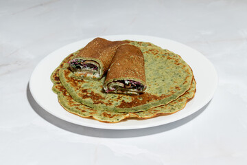 A close-up of green savory herb crepes with a fresh and healthy filling, emphasizing the texture and natural ingredients.