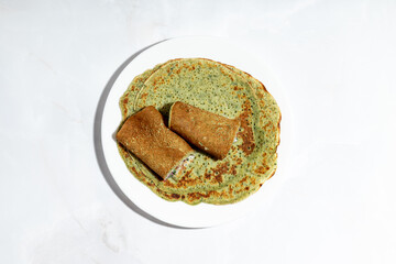 Close-up shot of crispy brown buckwheat crepes with a vegetarian stuffing, highlighting fresh salad leaves and dressing.