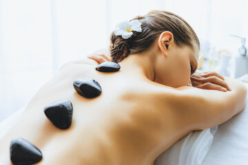 Hot stone massage at spa salon in luxury resort with day light serenity ambient, blissful woman...
