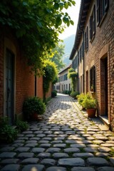 Obraz premium Sun-dappled cobblestone lane between aged brick buildings, lush greenery framing a picturesque passageway, tranquil atmosphere of a quaint village street