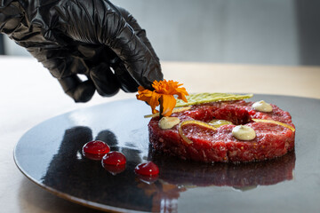 Chef garnishing beef tartare with edible flowers in luxury restaurant