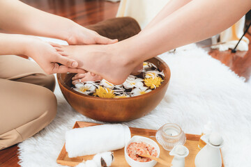 Woman indulges in blissful foot massage at luxurious spa salon while masseur give reflexology therapy in gentle day light ambiance resort or hotel foot spa. Quiescent