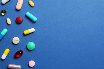 Various pills on blue background, top view