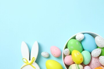 Happy Easter. Colorful eggs in a bowl and bunny ears on color background, space for text or advertising