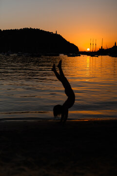 Silhouette of a child doing a handstand on a beach sunset in Soller