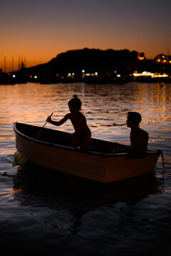 Children rowing a boat at sunset on a seas in Soller, Majorca