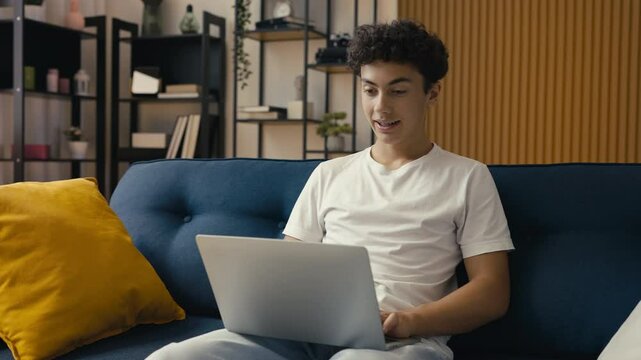 Pleased teen boy typing on a laptop, taking an online course, distance learning
