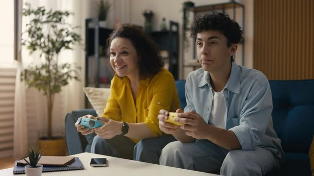 Adolescent son and his mother playing a video game at home, bonding over fun