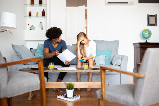 Couple reviewing bills with concern in modern living room