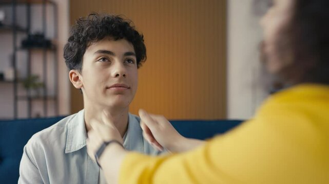 Happy mother pinching the cheeks of her teen son, feeling proud of her child