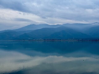 clouds and mountains reflected in the kerkini lake in greece