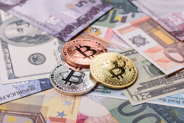 Round metal bitcoin on a background of paper banknotes of different currencies