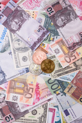 Round metal bitcoin on a background of paper banknotes of different currencies