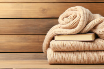 Cozy wool sweaters and a book stacked on a wooden surface for relaxation