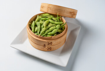 Edamame in a traditional Chinese steamer on a white background

